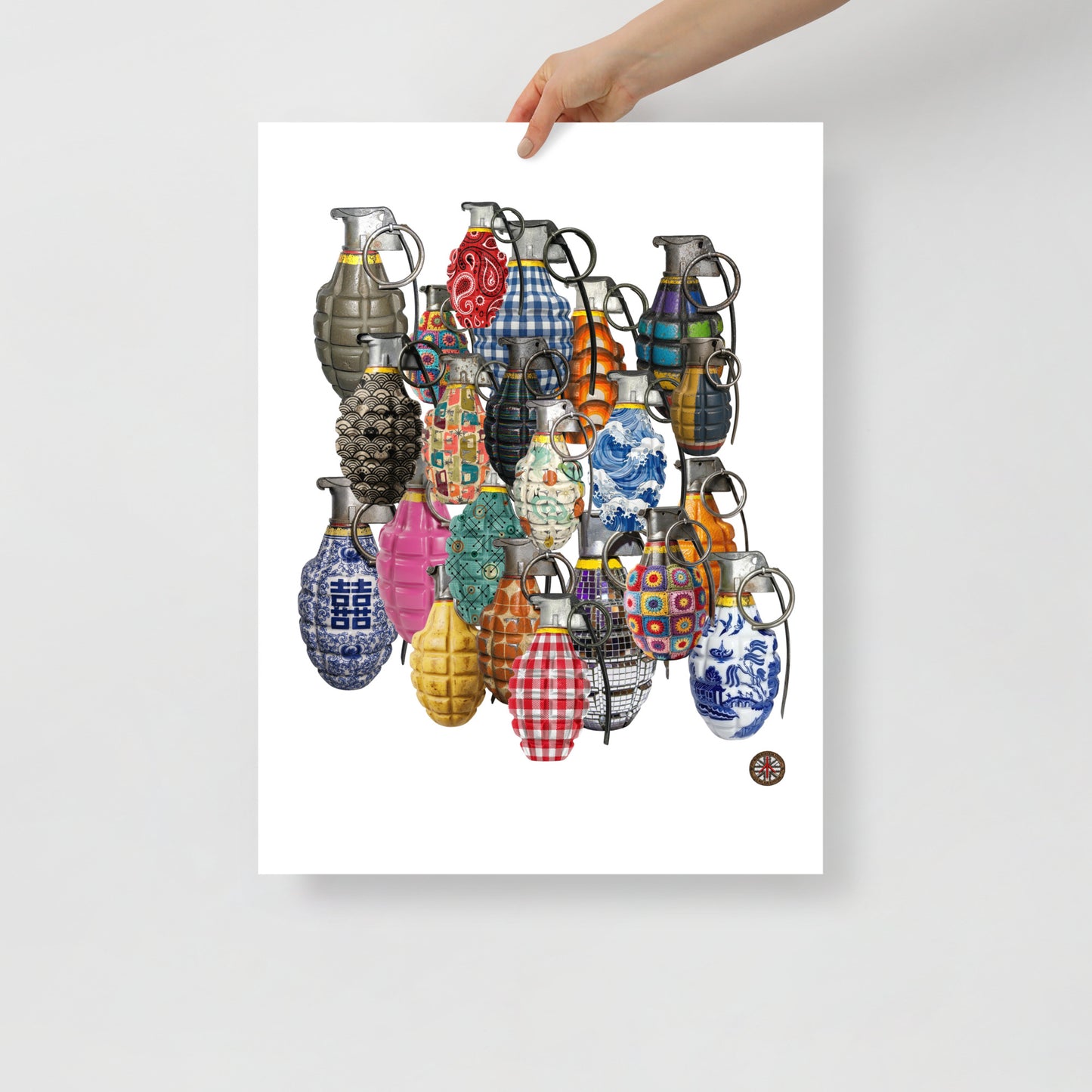 A hand holds a white art print featuring a collection of colorful, patterned hand grenades on a light gray background.