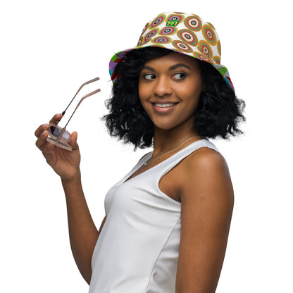 Woman wearing a  bucket hat featuring a retro circular target pattern on the crown in shades of green, red, brown, and beige on a white background, with a colorful geometric pattern on the inside. Reversible and breathable.