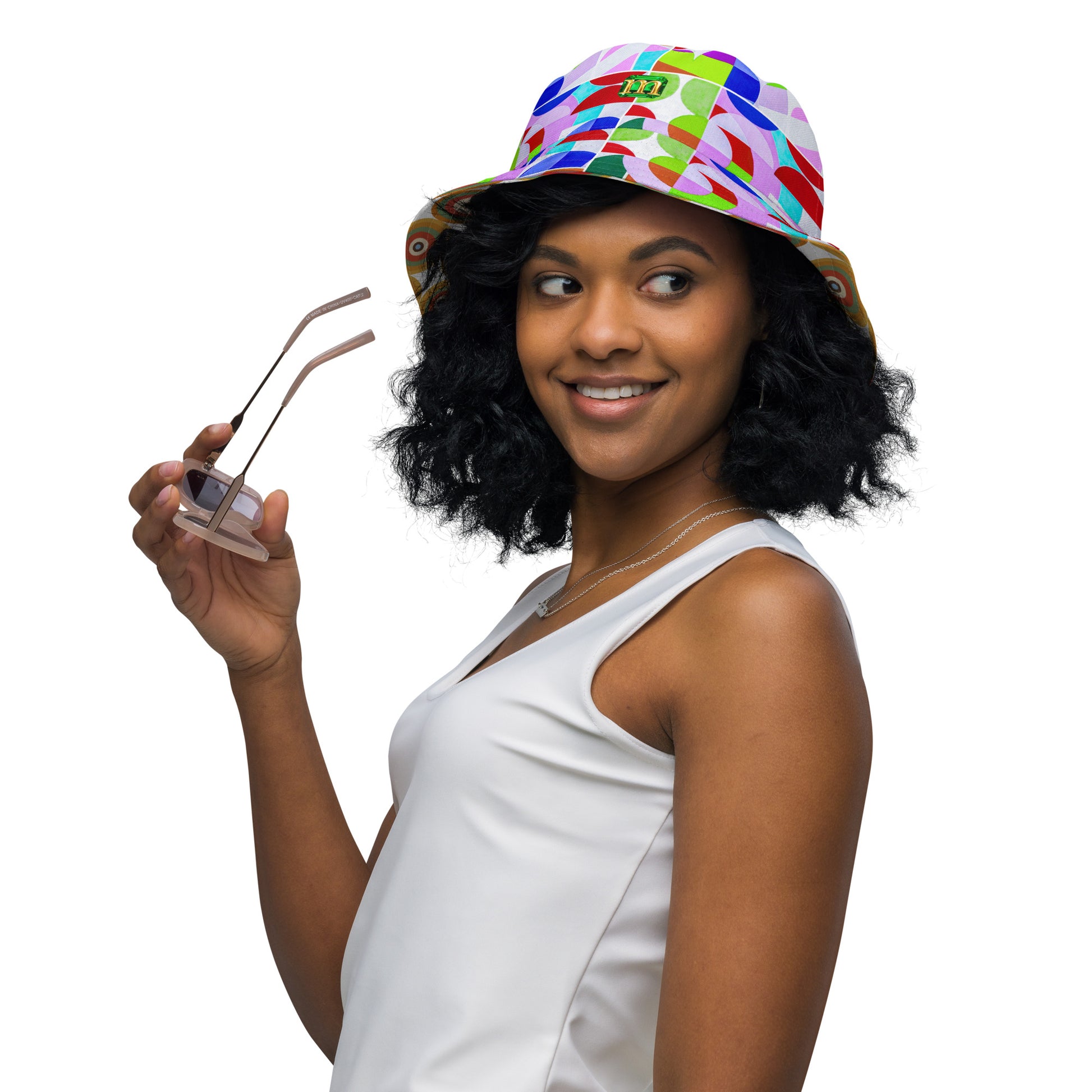 Woman wearing a circles design bucket hat and holding sunglasses on a white background