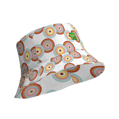 A white bucket hat featuring a colorful retro concentric circle pattern in shades of orange, red, yellow, green, and blue, with a small green logo on the side.