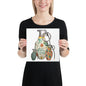 A woman wearing a black t-shirt holds up a square print featuring a colorful graphic illustration of three hand grenades with mid-century wallpaper designs on them on a white background.