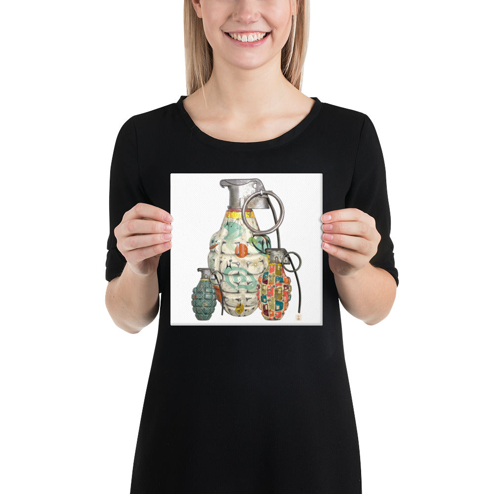 A woman wearing a black t-shirt holds up a square print featuring a colorful graphic illustration of three hand grenades with mid-century wallpaper designs on them on a white background.