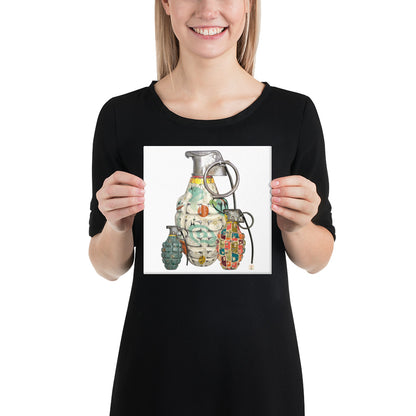 A woman wearing a black t-shirt holds up a square print featuring a colorful graphic illustration of three hand grenades with mid-century wallpaper designs on them on a white background.