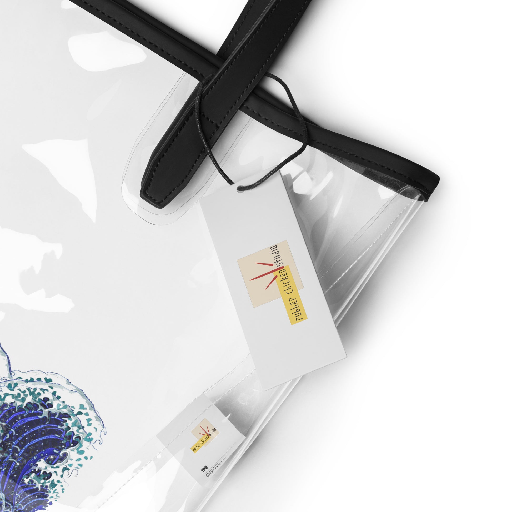 A clear plastic tote bag with black handles and trim, shown on a white background with branded paper tags attached.